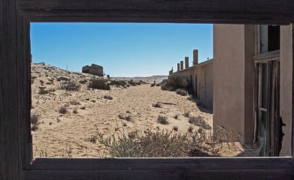 Blick aus dem Fenster auf Sand und die Häuser im Hintergrund