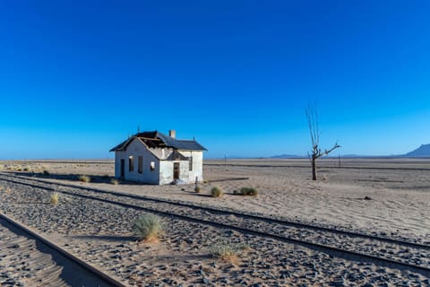 Bahngleise führen durch die Wüste auf ein Haus zu